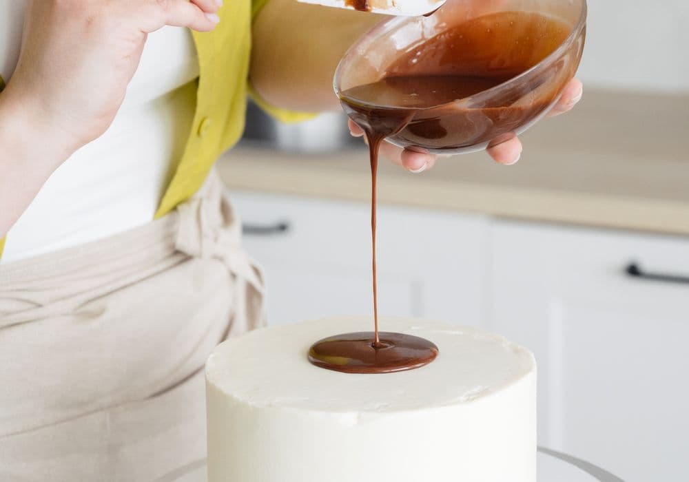 Pastry chef applying the final buttercream finish to wedding cake tiers